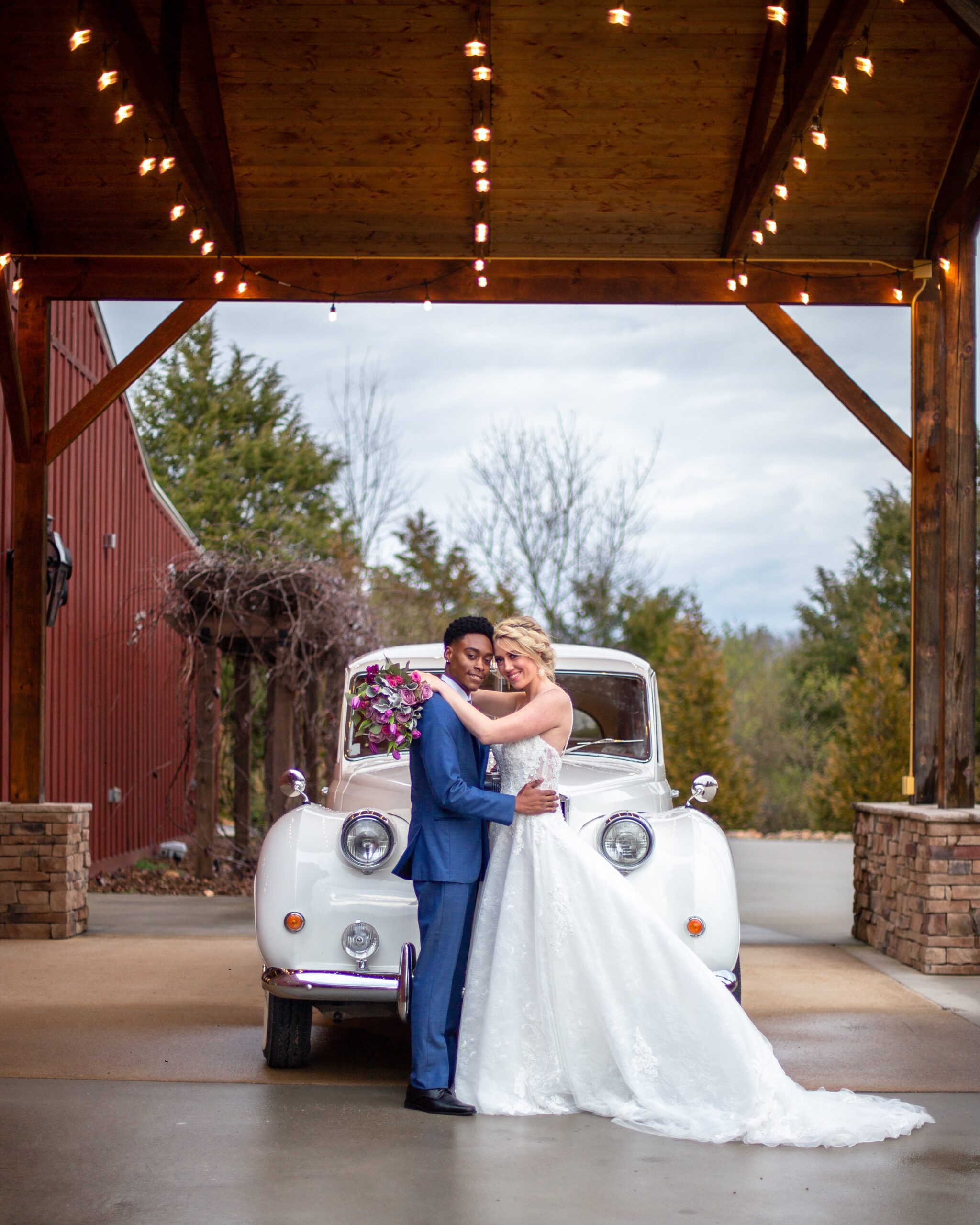 A happy couple posing with an antique car at The Vineyard Hall - A Rustic Wedding Venue